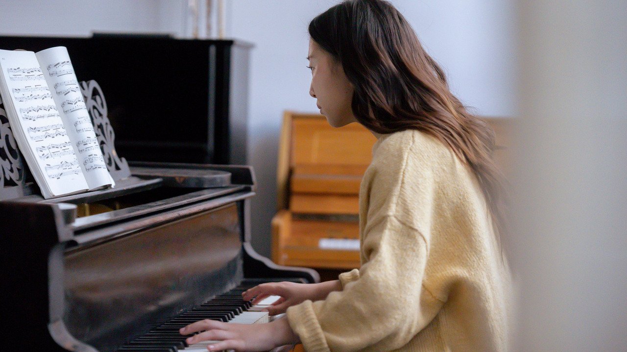 Focused first-steps practice at an open upright piano with visible keys