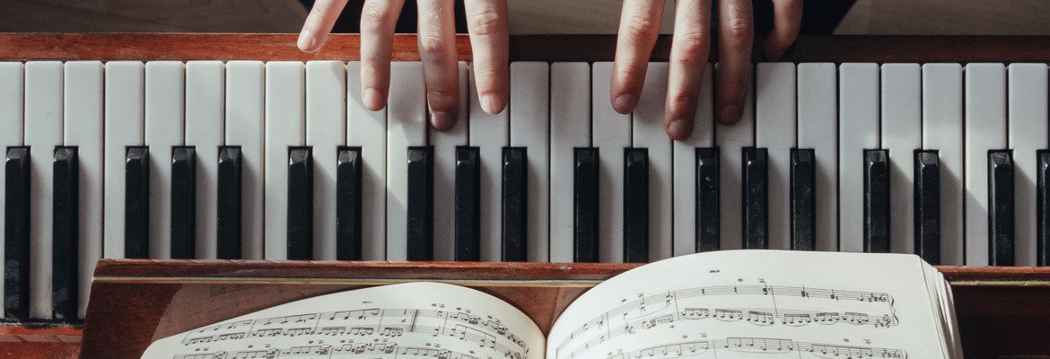 Hands and sheet music at an open piano during note-reading practice