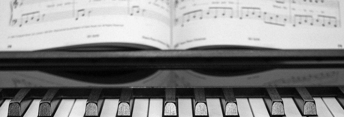 An open piano lesson book on the music stand above a row of piano keys