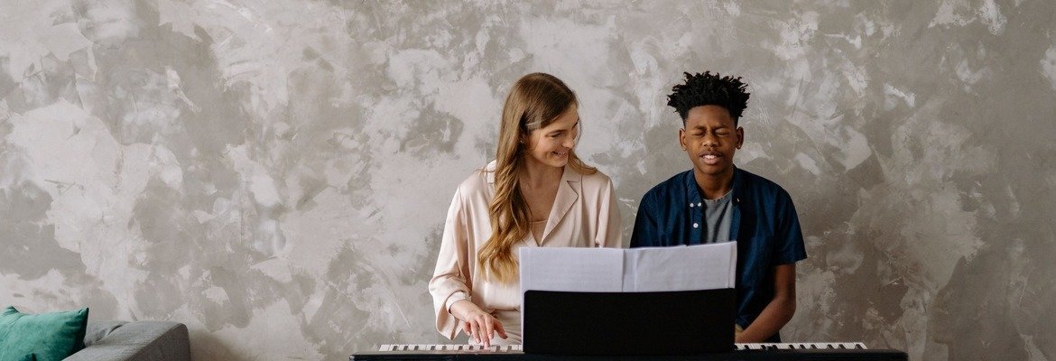 Piano teacher giving an in-home lesson at a student's piano