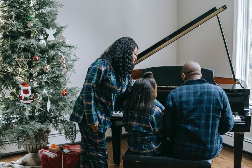 A child with her parents playing the piano